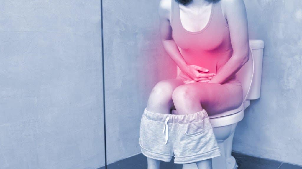 Frau mit Magen-Darm-Grippe >>Durchfall und Bauchschmerzen auf der Toilette