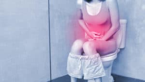 Frau mit Durchfall und Bauchschmerzen auf der Toilette>>Magen-Darm-Grippe